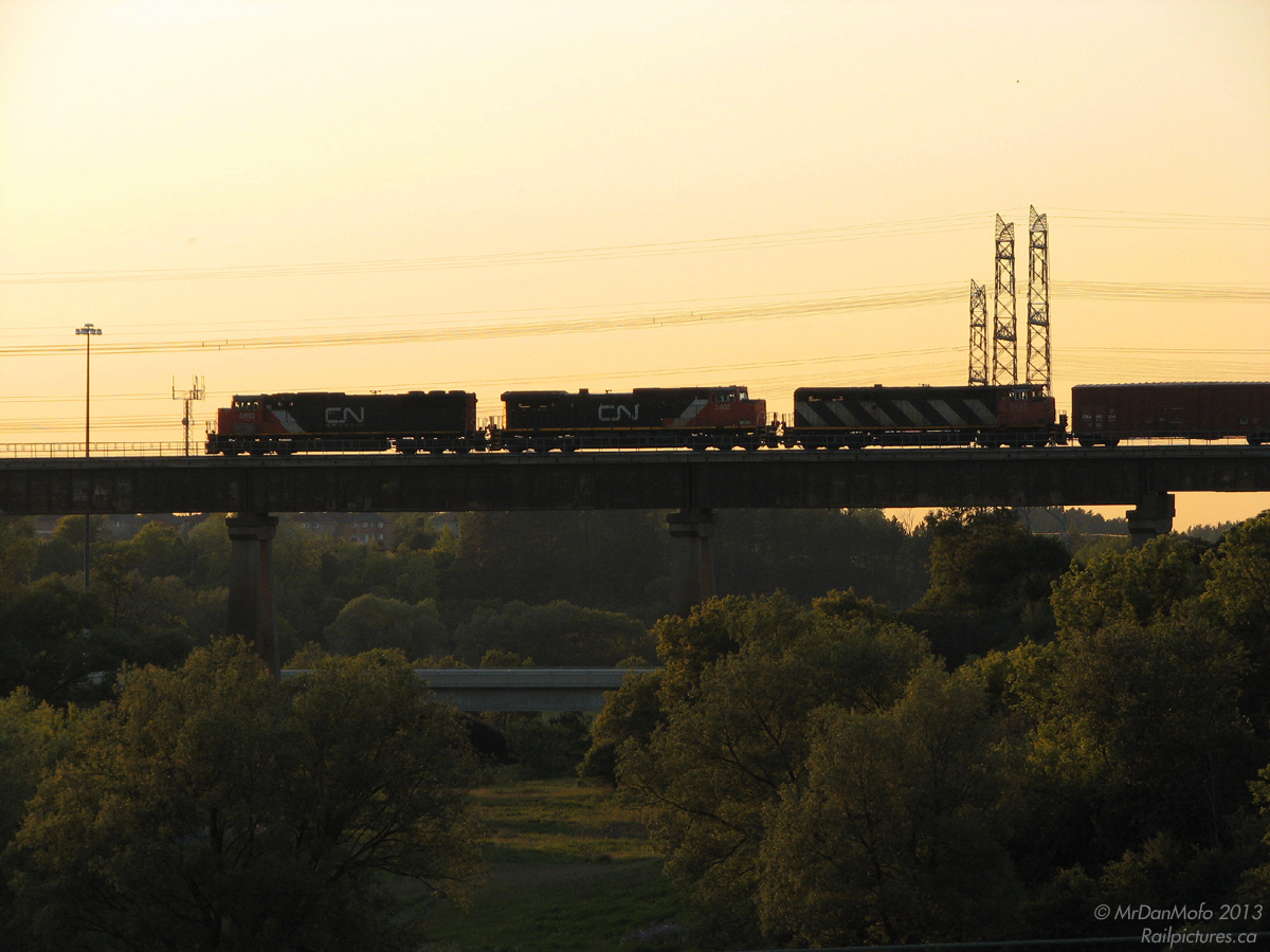 CN 395 was usually a regular evening departure (and in the FPON daze was always good for some foreign power) so could be tricky to shoot in good light depending on your location. On this day however, being a little over 4 miles from where it originated had its advantages: an all-CN consist of SD70I 5613, C44-9W 2602 and C40-8M 2422 are in charge of this evenings' 395, towering high as it crosses the massive Humber River bridge in Woodbridge (Vaughan) at sunset. Shot standing on the municipal boundary between Toronto and Vaughan: Steeles Avenue. The houses in the background are off Kipling Ave, and Highway 407 crosses part of the valley below.