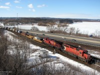 Heading north on the Canadian Pacific Hamilton Sub and about to begin the 18 mile ascent to Guelph Junction, an eastbound/northbound CP intermodal with CP 5941 leading 9813 (SD40-2/AC4400CW combo) heads through the plant at Desjardins, named after the Canal of the same name in the area, on a winter's mid-morn. A snow-covered Cootes Paradise is in the background under the blue sky, beyond the rail line and Highway 403.