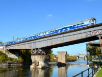 <b>Next stop Lasalle.</b> AMT 87 has 4 refurbished 700 series cars as it crosses the Lachine Canal southbound over CP's Rockfield Bridge. Next stop is Lasalle; after that it will cross the St-Lawrence River, on it ways to Candiac. For more train photos, check out http://www.flickr.com/photos/mtlwestrailfan/