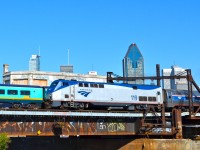 The outbound Amtrak Adirondack passes the inbound VIA Ocean/Chaleur about a mile south of Montreal's Central Station. They are passing the closed CN Wellington tower. Behind them is Montreal's skyline.