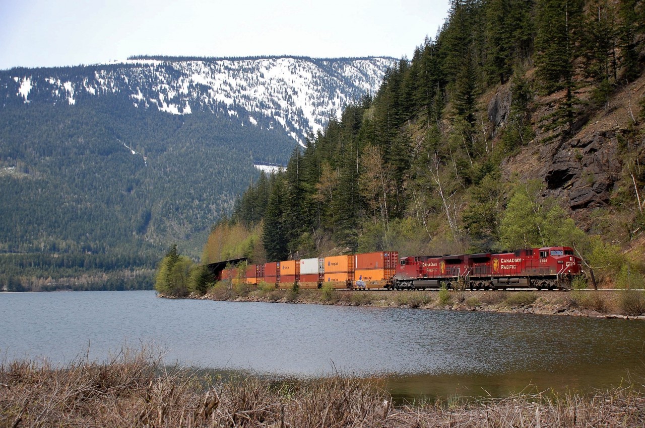 CP nos.9704&8577 emerge from a snowshed and bring an eastbound Intermodal alongside Three Valley Lake.