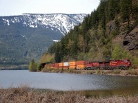 CP nos.9704&8577 emerge from a snowshed and bring an eastbound Intermodal alongside Three Valley Lake.
