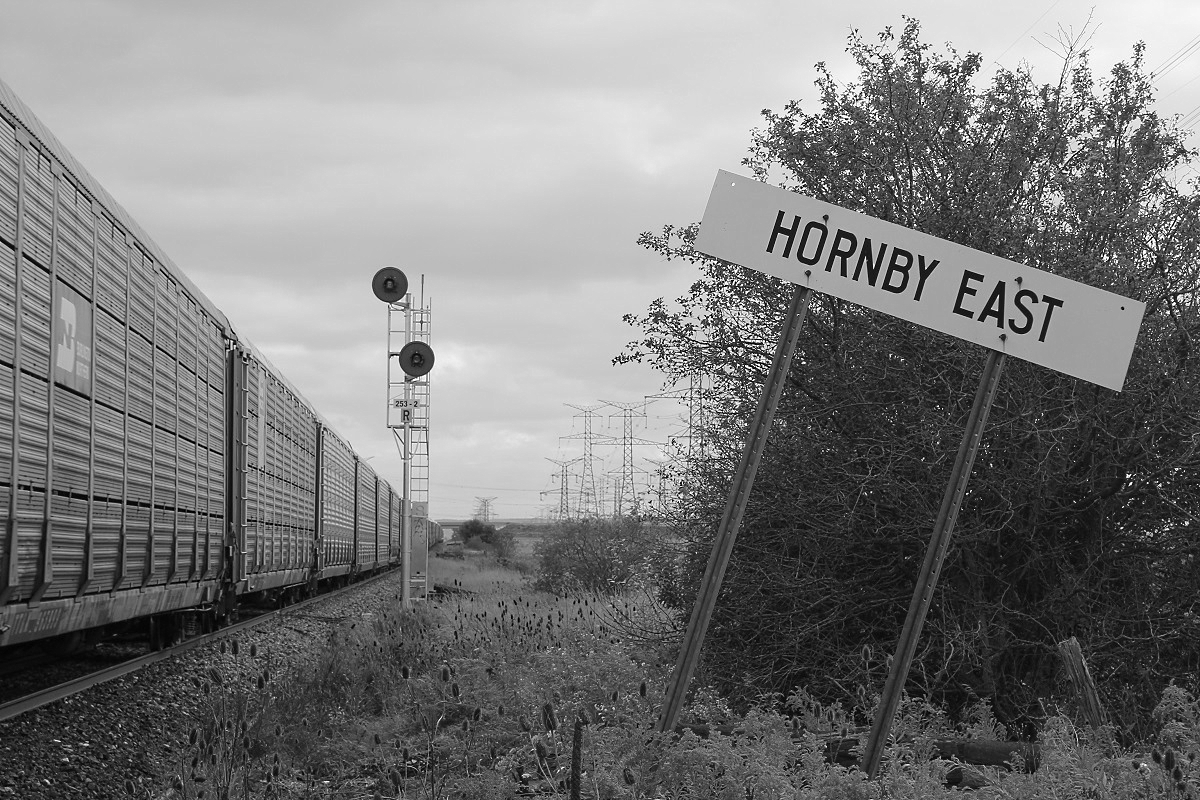 A nice black & white shot of autorackers flying by and the old "Hornby East" sign.