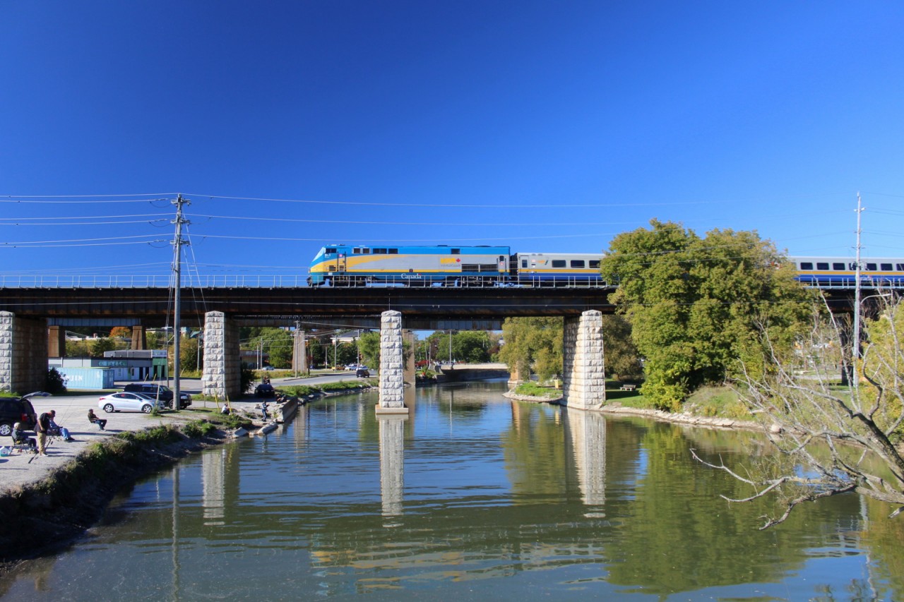 VIA rail train rolls over port hope bridge as tons of people fish the Ganaraska river