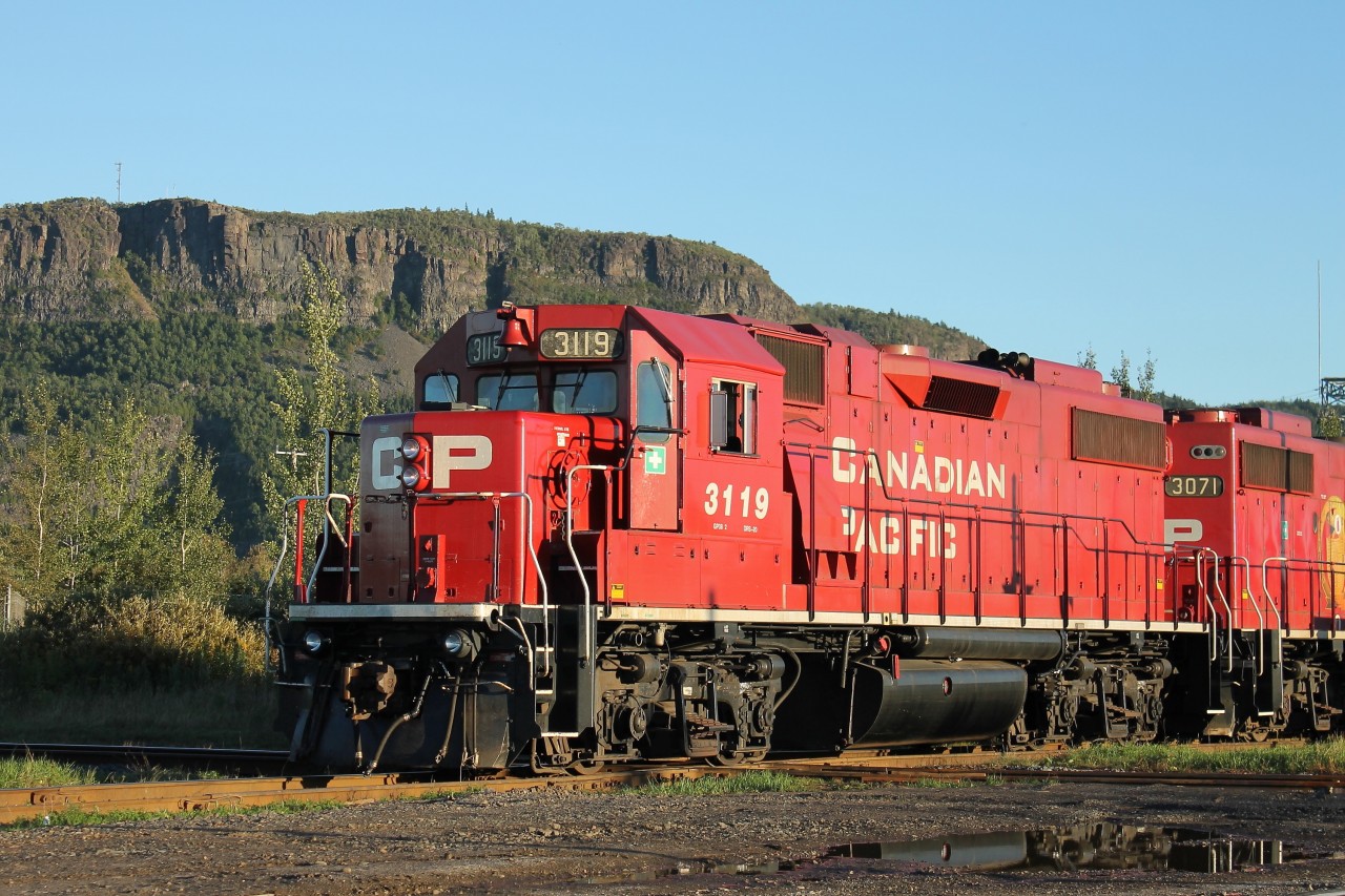 In the lee of Mount McKay and the evening sun, the afternoon roust is travelling from CP’s Westfort yard along the Farm Lead to service several industries in this corner of Thunder Bay. The engineman had previously stopped the units, a pair of GP38-2’s – 3071 and 3119 – clear of the ‘other’ CN diamond in Thunder Bay and contacted the CN RTC in Edmonton for permission to cross.  Upon receiving a clear aspect from the dwarf signal protecting the interlocking, CP 3119 is now on top of the diamond crossing as the units proceed towards Resolute Forest Products.