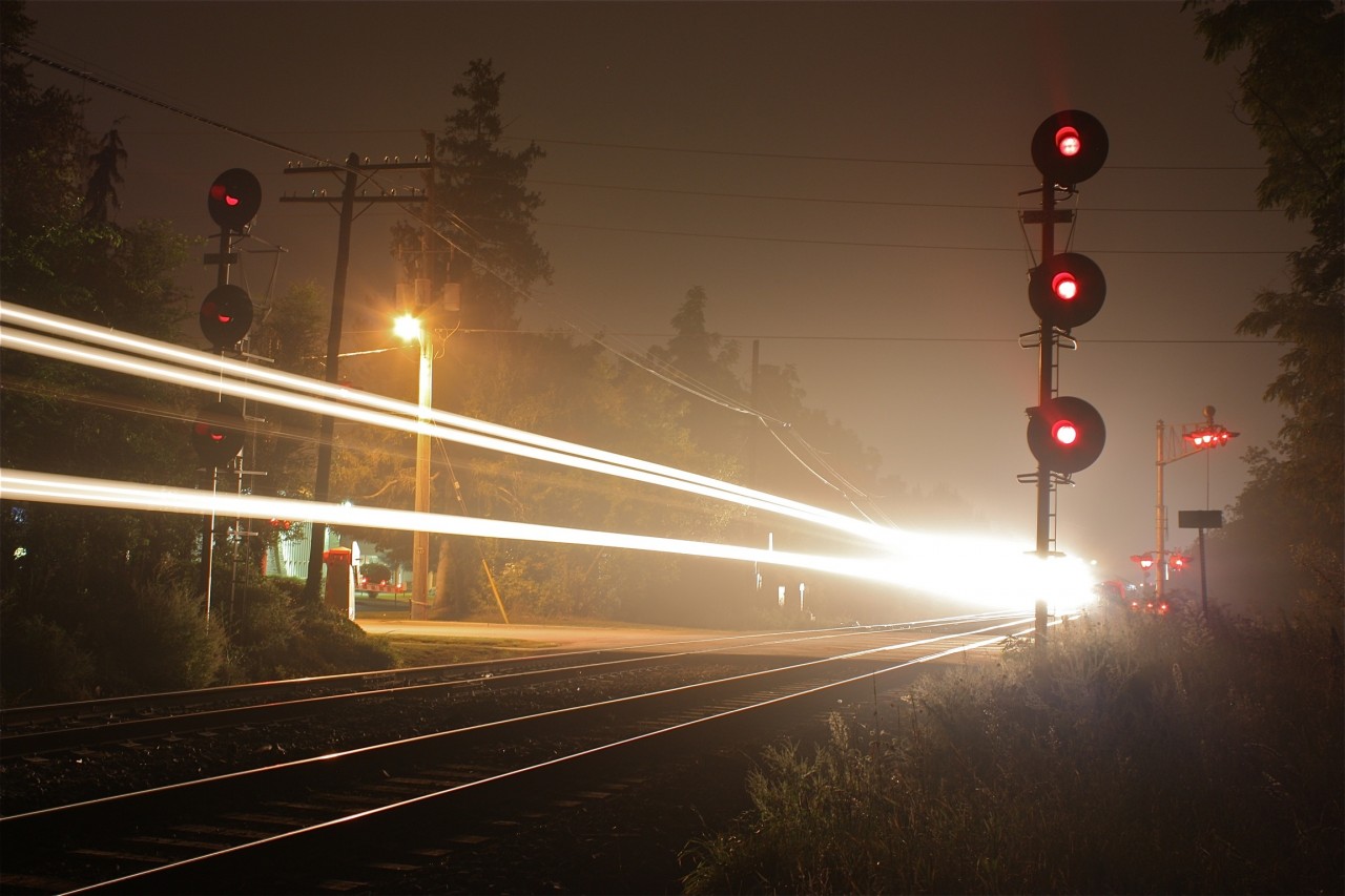 CP 8803 and AC4400 and SD40 companions steak past Martin Street crossing and the Milton West signals with light fog adding to the scene.