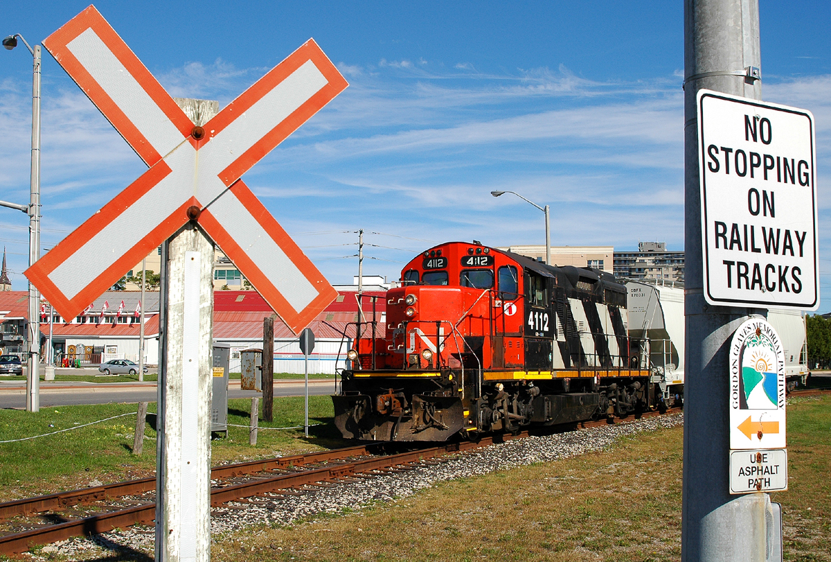 CN 580 making it's way downtown with one hopper, framed by a pair of railway related signs
