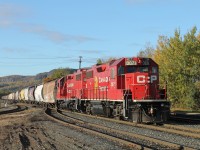 A pair of GP38-2 ‘s, 3071 and 3119, are switching out bad orders on the lead track at the east end of CP’s Westfort Yard in Thunder Bay. The fall colours are in perfect harmony with the red engines and the multi coloured grain hoppers stretching back towards Mount McKay.