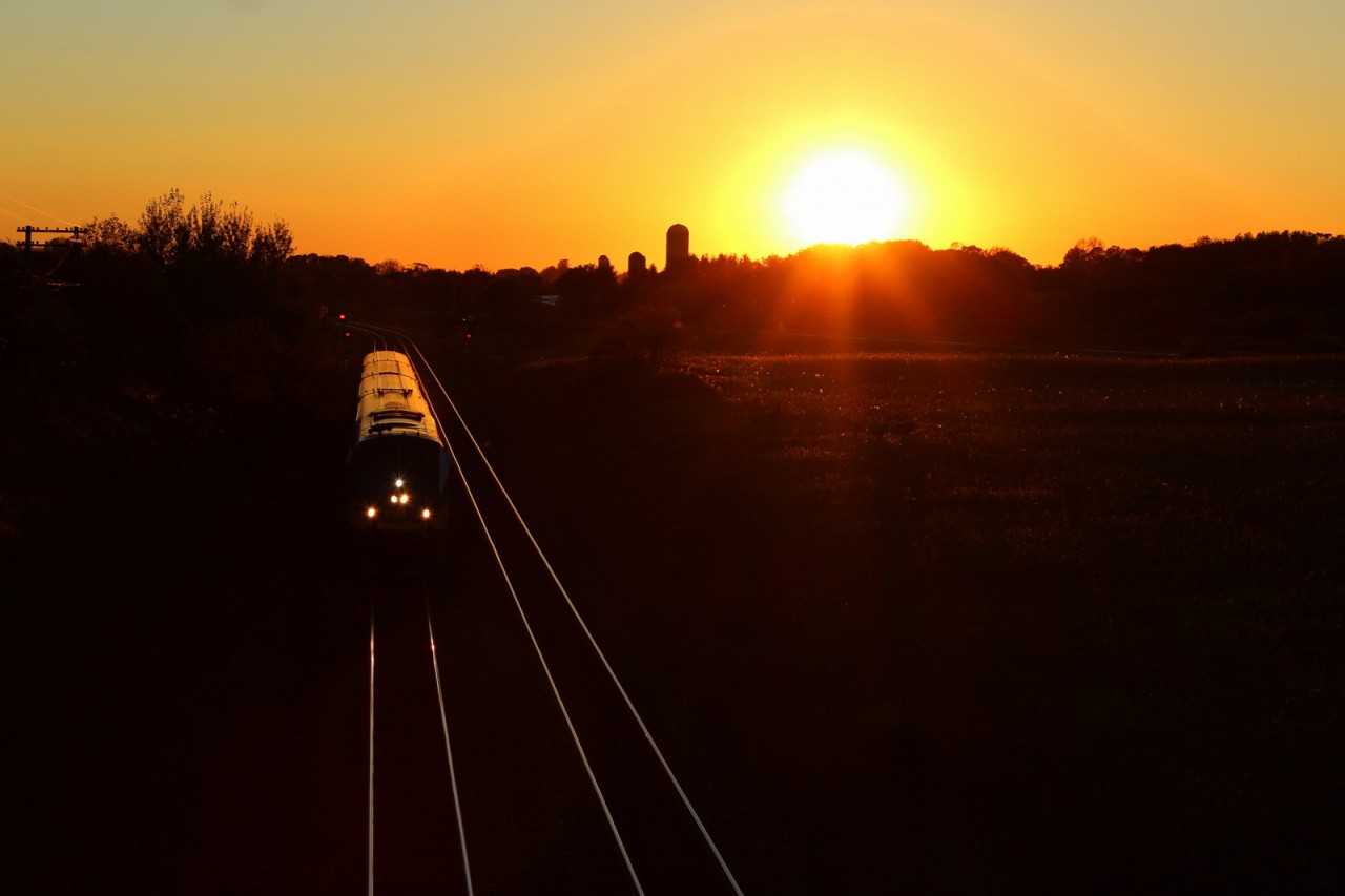 A eastbound VIA train fly's through the signals and under the Newtonville road bridge as the sun sets