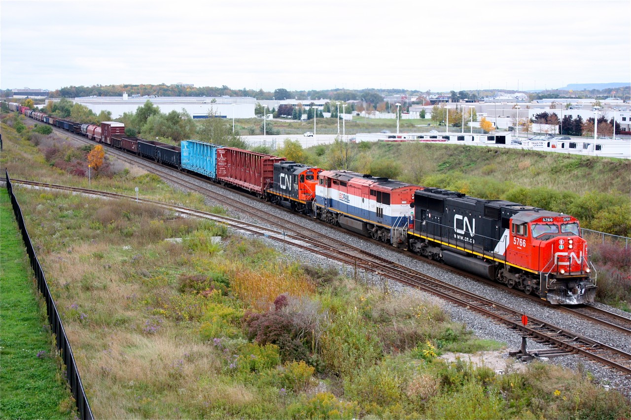 CN 5766, BC Rail 4610 and CN 7058  are about to duck under James Snow Parkway while heading their train east towards Toronto yard. This angle is not possible on sunny days as the sun is on the wrong side so cloud cover came in handy this day. The town of Milton is in the background with the Niagara Escarpment beyond it.