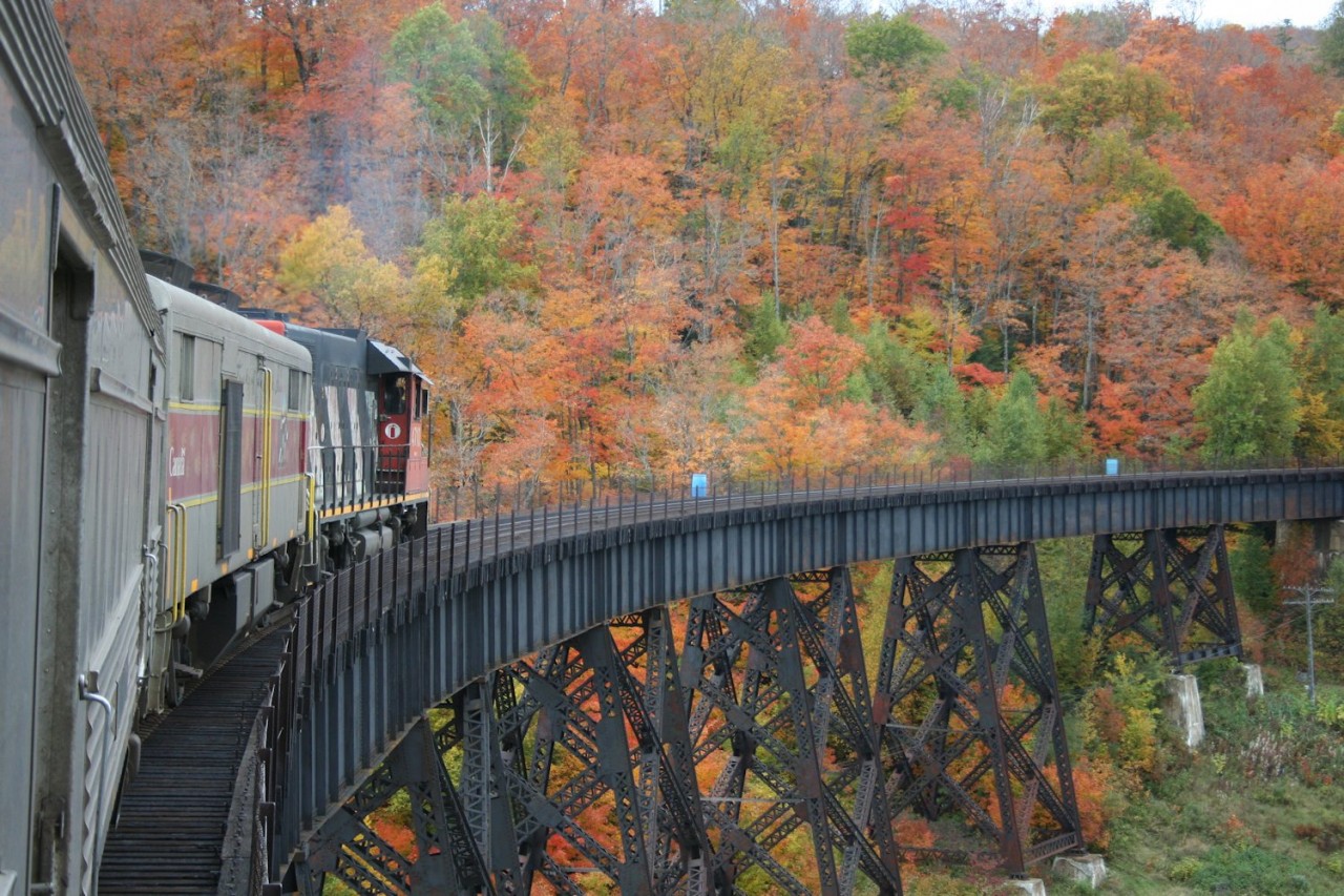 CN 631, the northbound Algoma Central regular passenger train from Sault Ste. Marie to Hearst, crosses the always spectacular Montreal River trestle at Montreal Falls. Equally spectacular are the peak fall colours on the hills and in the river valley.