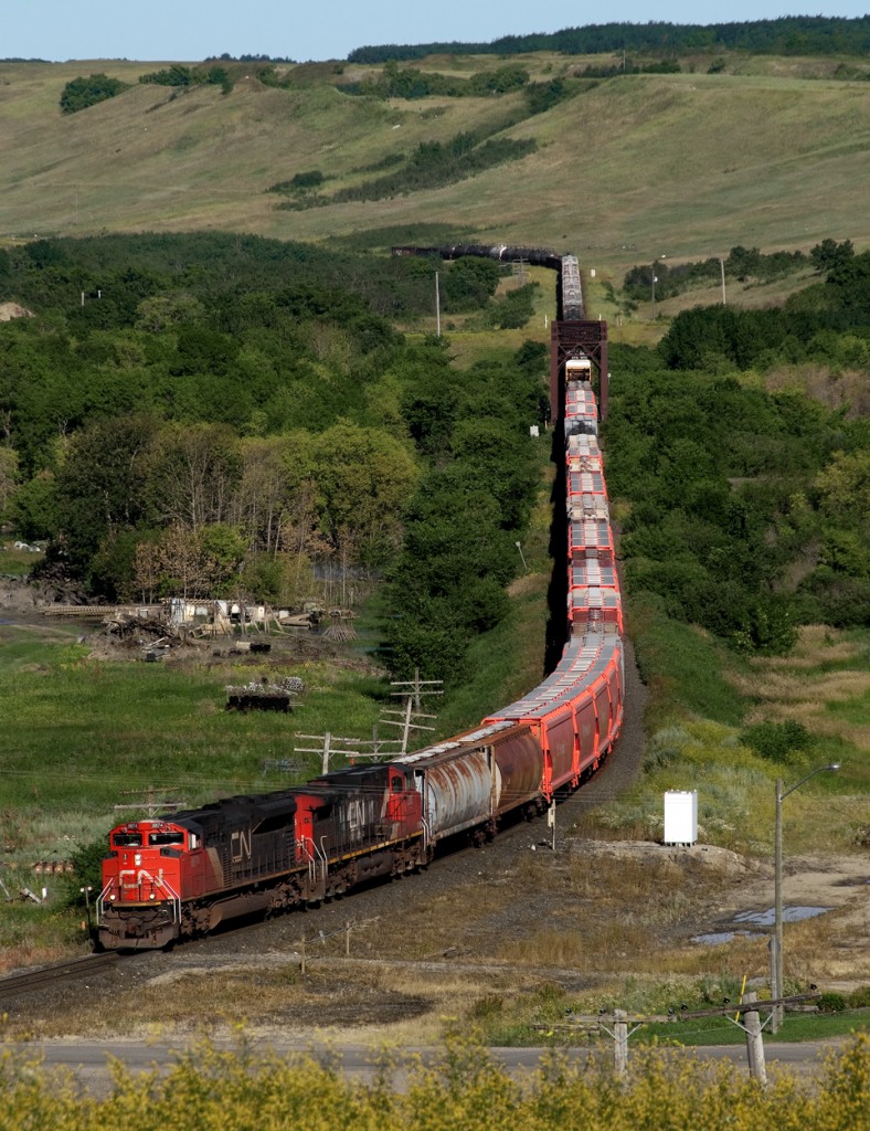 Eastbound short haul train 404 crosses the Assiniboine River in western Manitoba, having descended via the Quapelle Valley. The train has just picked up potash loads at the top of the hill loaded at Rocanville Sylvite Mine.
