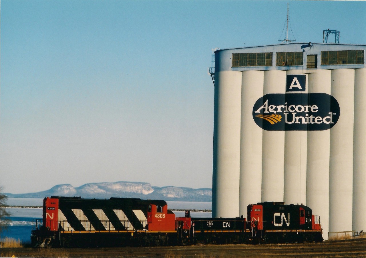 The morning yard turn out of Thunder Bay North has arrived at the Agricore A grain elevator situated on the north side of the Thunder Bay waterfront.  In the background above yard power cn4808, cn265, cn7224 there is ice in the bay and snow on The Sleeping Giant. The railways are busy switching loads in and empties out at the elevators as the lake boats arrive at the elevators for the spring grain rush.