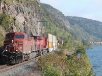 Train 113 led by CP 9623 and CP 8878 skirts along the shore of Lake Superior near Cavers. Rock slide detector fences are in place alongside the vertical rock faces where the first contractors blasted the roadbed out of the side of these cliffs.