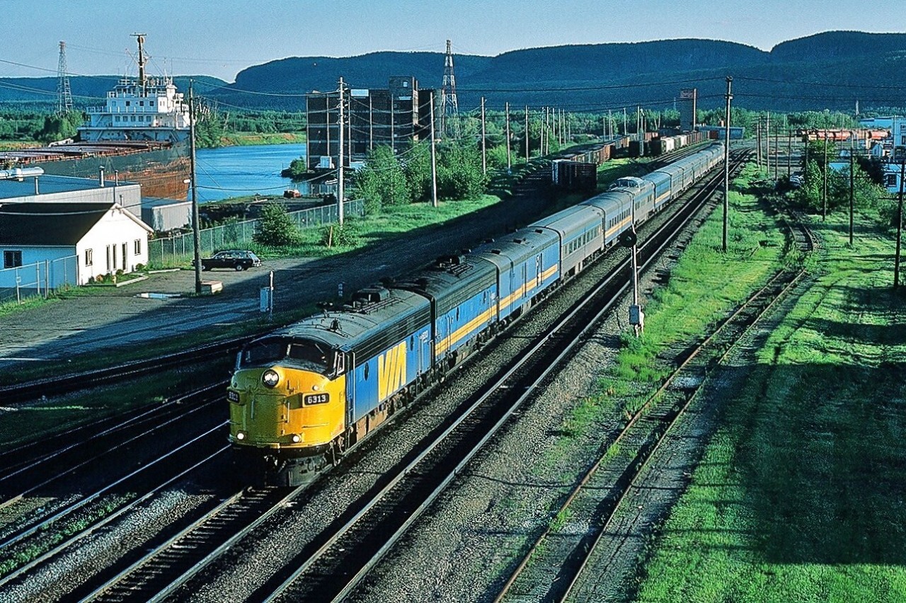 Fifty two hours, twenty minutes and one thousand eight hundred ninety two miles after the Vancouver departure, primarily on CP Rail (a division of Canadian Pacific Limited) – average speed 36.2 mph – an on time Via Rail train #2 is one mile west of the CP Rail Thunder Bay station (formerly Fort William). After the early evening Thunder Bay station stop Via #2 schedule requires  25 hours to travel the nine hundred ninety four miles – primarily on CP Rail -  to Montreal's Central Station, average speed 39.7 mph.  


Via Rail 6313 was re-manufactured March 1985 from GMD FP9A CN6526. April 2002 Via 6313 and 6307 (ex CN6515) were sold to Ohio Central.  



June 19, 1985 Kodachrome by S. Danko


 More Thunder Bay:

    last sight 1990  


  Pacific Avenue overpass  


More Northern Ontario:


   exceptional  


   Centre of the Community