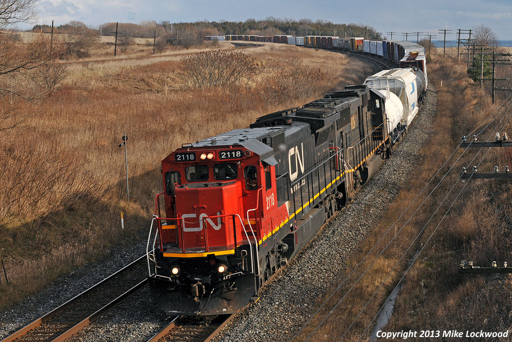 A rare catch these days, CN 2118 and IC 1026 lead a 369 with all the power on the head end (no DPU). This is somewhat worthy to note, as earlier they had a broken knuckle near Grafton in hogback country; a common occurrence before, and the reason many tonnage trains receive, DPU's on the Kingston Sub. I've seen examples of both the 2100 series C40-8's and the 1000 series SD70's in use as remotes with 2200/2300/8800/8900 leaders, but never together as a lead and remote pair. Perhaps they can't work together in DPU, but regardless, a nice sight in a world flooded with wide nosed locomotives. Thank you Delic. 1337hrs.