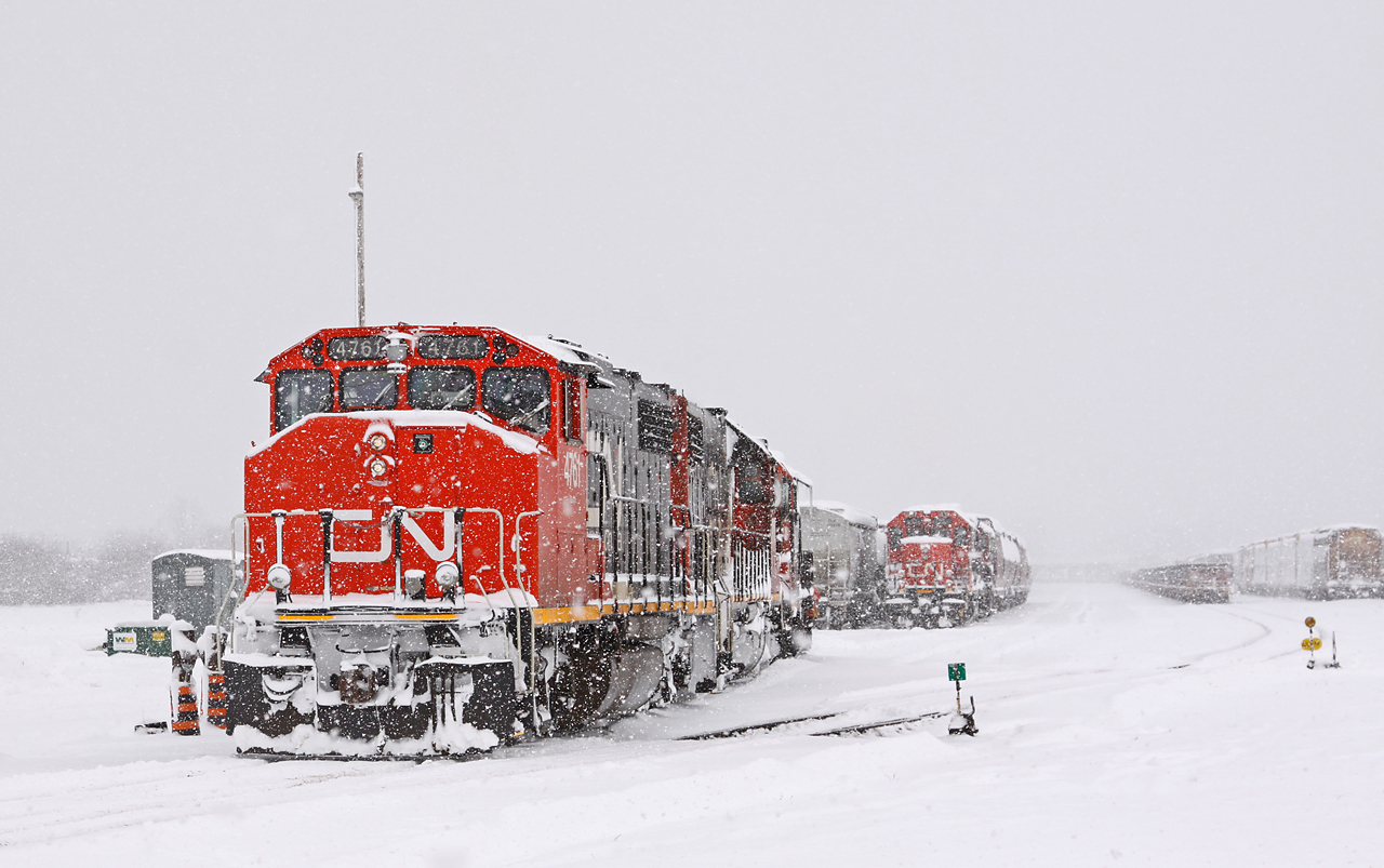 Winter has come early to Southwestern Ontario, or at least part of it. Amid a raging blizzard, CN 439's power backs onto their train as CN 511 looks on. Today's power is bright and shiny CN 4761, 4700, and a very cold CN 4116 for Chatham. The crew reported that there was no snow west of the Melrose diamond - I bet 4116 is looking forward to thawing out after spending the night accumulating snow in London! CN 511 (4728 west) would follow them out of the yard to work the grain elevator at Kerwood.