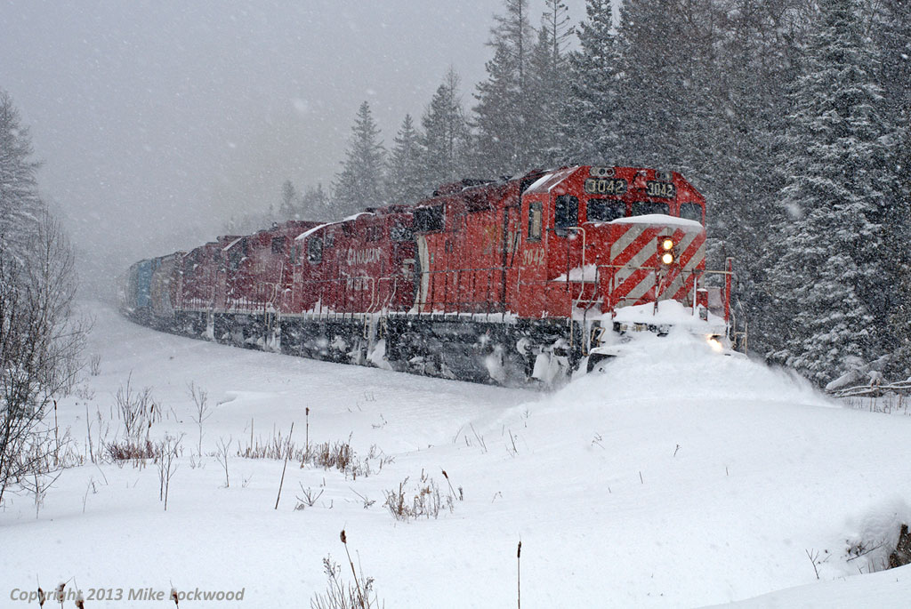 Hands down, the best chase I've ever done on the Havelock Sub, and I've done a few, was January 18, 2009. It had snowed much of the previous night on the moraine, and kept snowing, heavily at times, all the way from Toronto to Peterborough, where I finally ended the pursuit. Shot after shot after shot of them running through a winter wonderland, all the time pushing a wall of snow up to, and sometimes above, the top of the plow at least as far east as Cavan Station. So much snow that the ditchlight on the hogger's side has shorted out (it was working when they left Toronto Yard. Pictured is the train blowing for the Porter Road crossing south of Bethany, behind CP 3042, 8200, 3045, and 3105 with 30 cars on the headpin. 1217hrs.