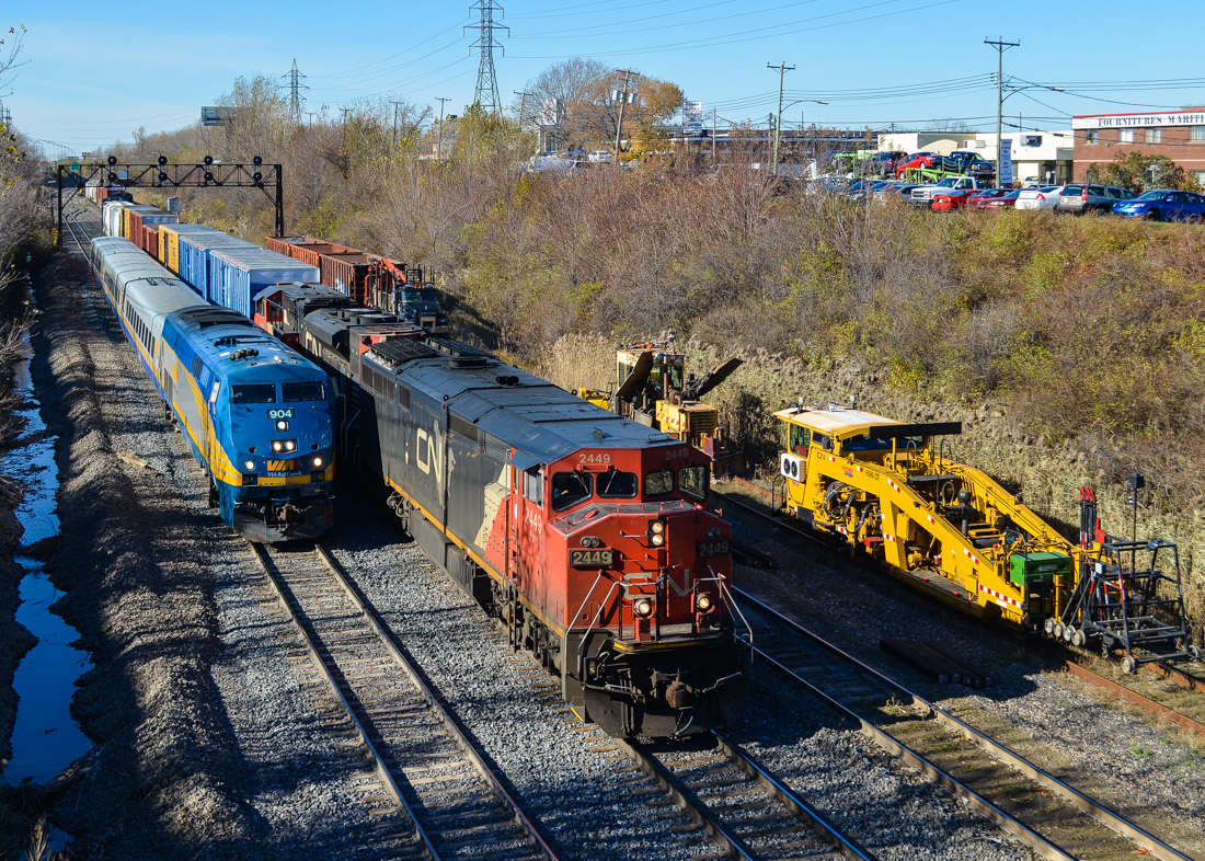 A pair of eastbounds. VIA 52 (inbound from Toronto) with VIA 904 in the lead is about to blow by CN 394 (bound for Richmond, Qc) which has just left nearby Taschereau Yard. Leading the CN train are CN 2449 (with modified radiators) and CN 8945. To the right is some MoW equipment; CN has been doing a lot of trackwork on the Montreal Sub recently. For more train photos, check out http://www.flickr.com/photos/mtlwestrailfan/