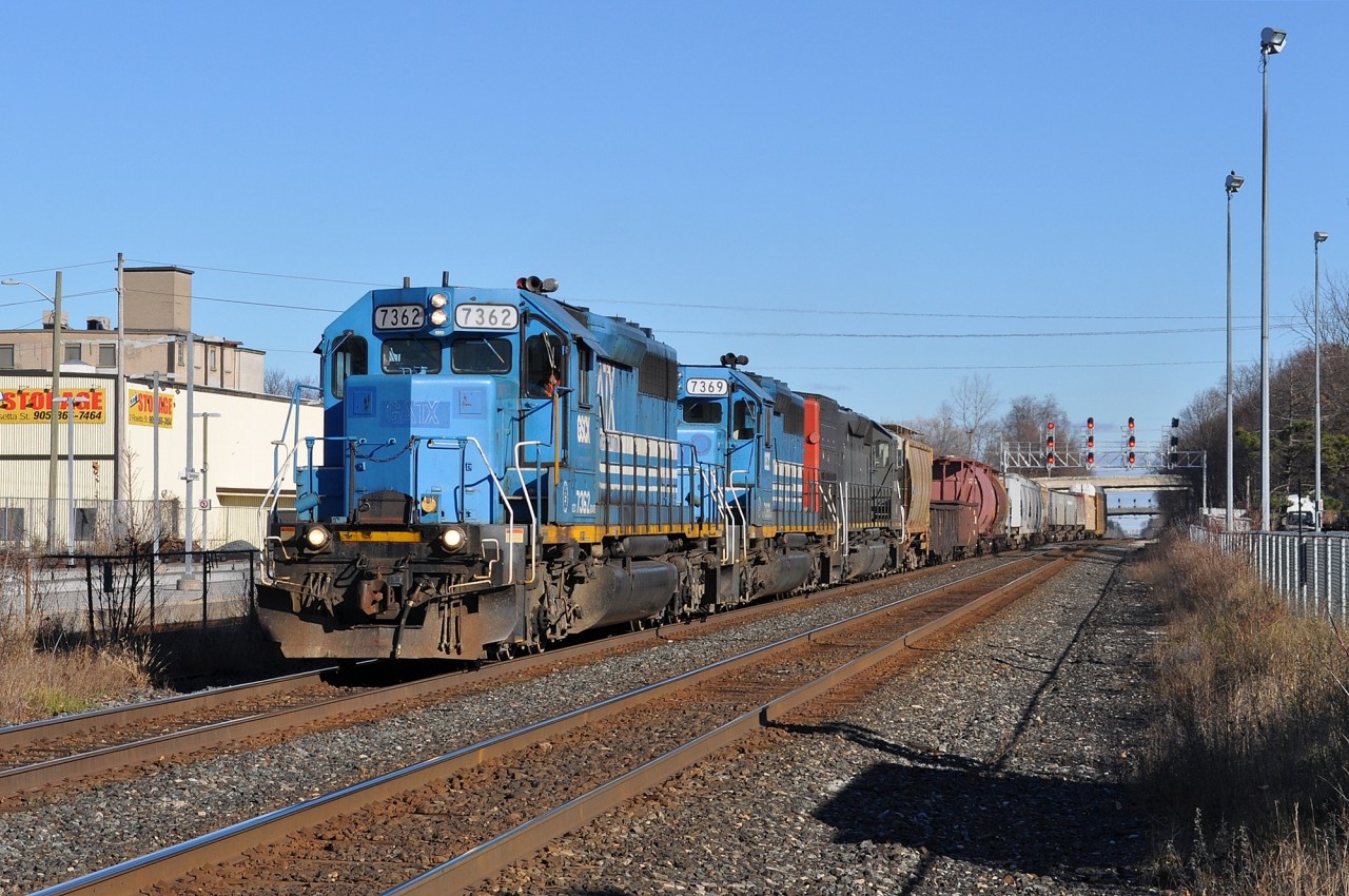 A short 431 with just 14 cars is easy work for this SD trio. At left, empty tracks and platforms await the arrival of the afternoon GO trains. The building in the background is the former Alliance Paper Mill. Built in 1910 as the Georgetown Coated Paper Mill, it was one of two rail-served mills that once operated here. It shut down in 1977.