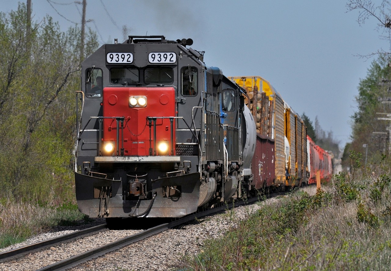 Returning from MacMillan Yard, 431 passes through the rolling countryside between Acton and Rockwood. On this warm spring day the loads included a gondola of utility poles and a string of Potash Corp hoppers.