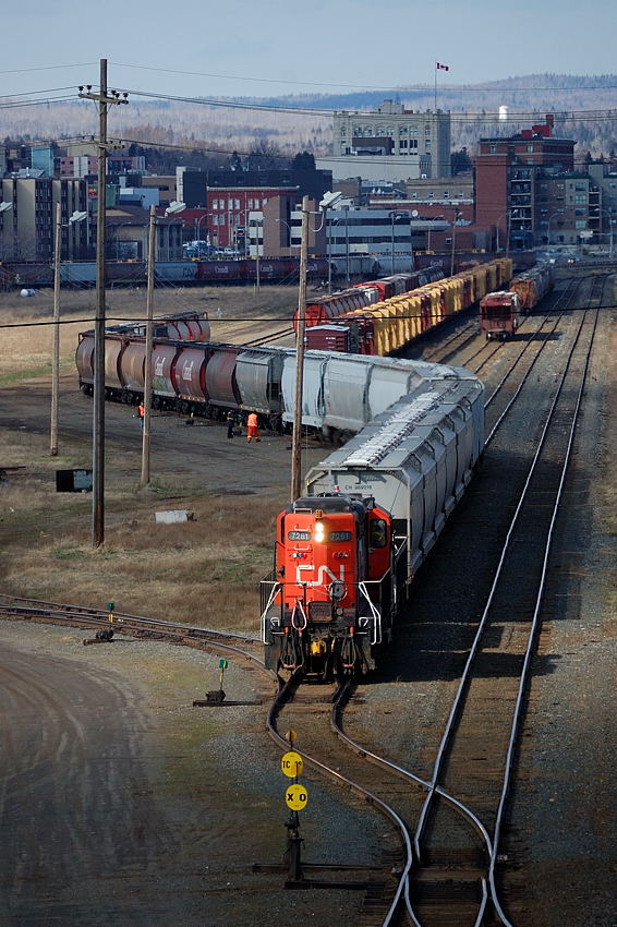 One of my favourite spots to shoot in Thunder Bay was from the Central Ave overpass looking over CN's Port Arthur yard. Action was limited on the best of days, but it would usually guarantee watching the afternoon yard switching grain cars to/from the local elevators and miscellaneous interchange traffic from CP. Thunder Bay's geographic location on Lake Superior made it hard to forecast weather, some days would call for nothing but sun and it would turn cloudy/rainy or vice versa, however it would normally cloud over to the west every evening while to the east over the lake it would remain clear. When it would work out, some dramatic scenes would take place. Here I caught the "15 Port Arthur" switching loads out of Canada Malt while a sucker hole catches CN 7261 as its crew kicks a string of 14 cars into a track in a yard marshalling "Easts", "Wests" and "South's".