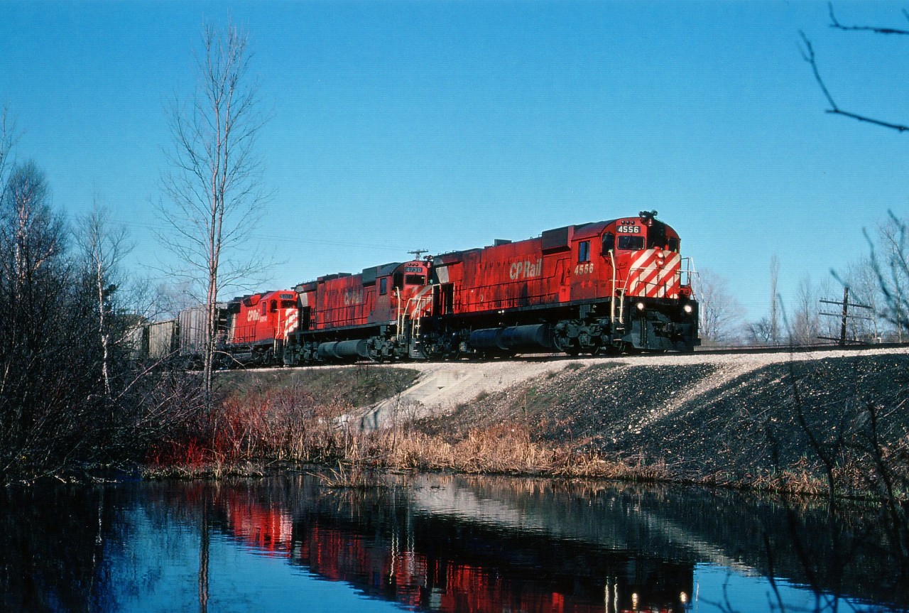 Between First Line and the switch leading off to the Hamilton Sub. on the CP main between London and Toronto there used to be this little frog pond. Fed by a small stream, of which the culvert under the CP can be seen dead centre in this image. It made a nice photo location, but, alas, over the years silt has rendered this spot just a bit of a bog in the weeds. After falling on my (bleep) a couple of times and getting thoroughly soaked, I gave this location up.  But there were some nice images to be had; such as this CP 4556, 4730 and 5014 early morning eastbound. Beautiful mornings like this, combined with interesting power, made for a great day to be trackside.  April 18, 1979.