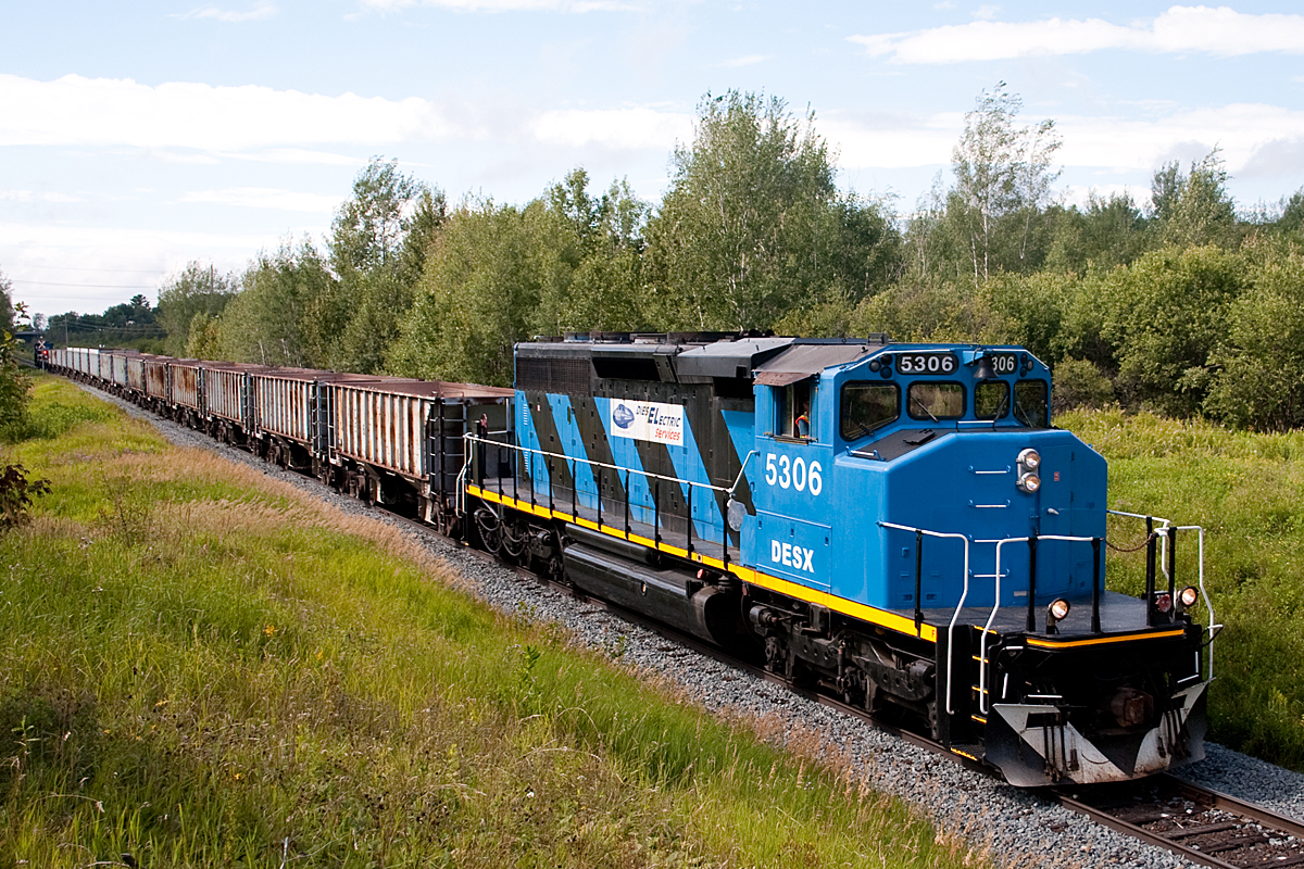 Rolling along at a mind-numbing 10mph, the eastbound ballast work train is a mile or two out of the tiny town of Bar River, which makes Echo bay (my previous shot) look like a bustling urban center. 

They will be in the 10mph zone for track speed for another hour or so, until the restriction is lifted east of Thessalon.

The hope is that with work trains just like this one, the slow orders will gradually diminish, until it's somewhat of a highball (probably around 25)to the crew change at McKerrow.