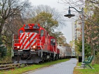 While everyone else talks about snow, it's a rainy autumn afternoon in Guelph. The daily Monday to Friday roadswitcher out of Guelph Jct is seen heading back south to finish off PDI Elizabeth St and the Liquid Yard after switching AOC Canada on the South Industrial and lifting the interchange which consisted off two hydrochloric acid tank cars (PDI Liquid Yard), a plastic hopper (PDI Elizabeth St) and a lime hopper (Owens-Corning Fiberglas) from the GEXR. The trail I'm standing on to get this photograph is the old CPR mainline which was torn up to make way for the trail, the train is on the old siding which is now the new mainline. 