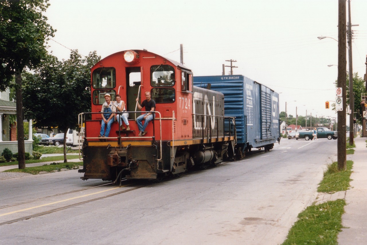 Brantford isn't the only city that has featured street running in the past 25 years. Here's an example. Shown is CN 7724, an SW1200, (off roster by 1990)trundling down the middle of Welland Ave in St. Catharines back on the early eve of July 1, 1987. The stoplight in the background is Niagara St. Trackage has been paved over for many years, but this stretch used to run from the old NS&T trolley yard area just out of sight a block down on the right, and curved off the Avenue left in another 1/4 mile or so, over to the GM plant on Ontario St. Little is left now, as industry retreats from the core of the city as it has everywhere else. Often riders were seen on this job, as in the case here, probably hitching a ride down to an establishment near GM known by the inebriated locals as the "Ruptured Duck", and to the regular city folk as the "Golden Pheasant". GM is gone from this part of the city, but I believe the ol' Duck is still in business. CN 7724 was renumbered from 7024 in 1985 to accomodate switcher rebuild programs.