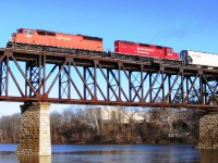 Westbound hopper train crosses the Grand River after stopping at Galt station. Viewed from the west river bank in Riverbluff Park.