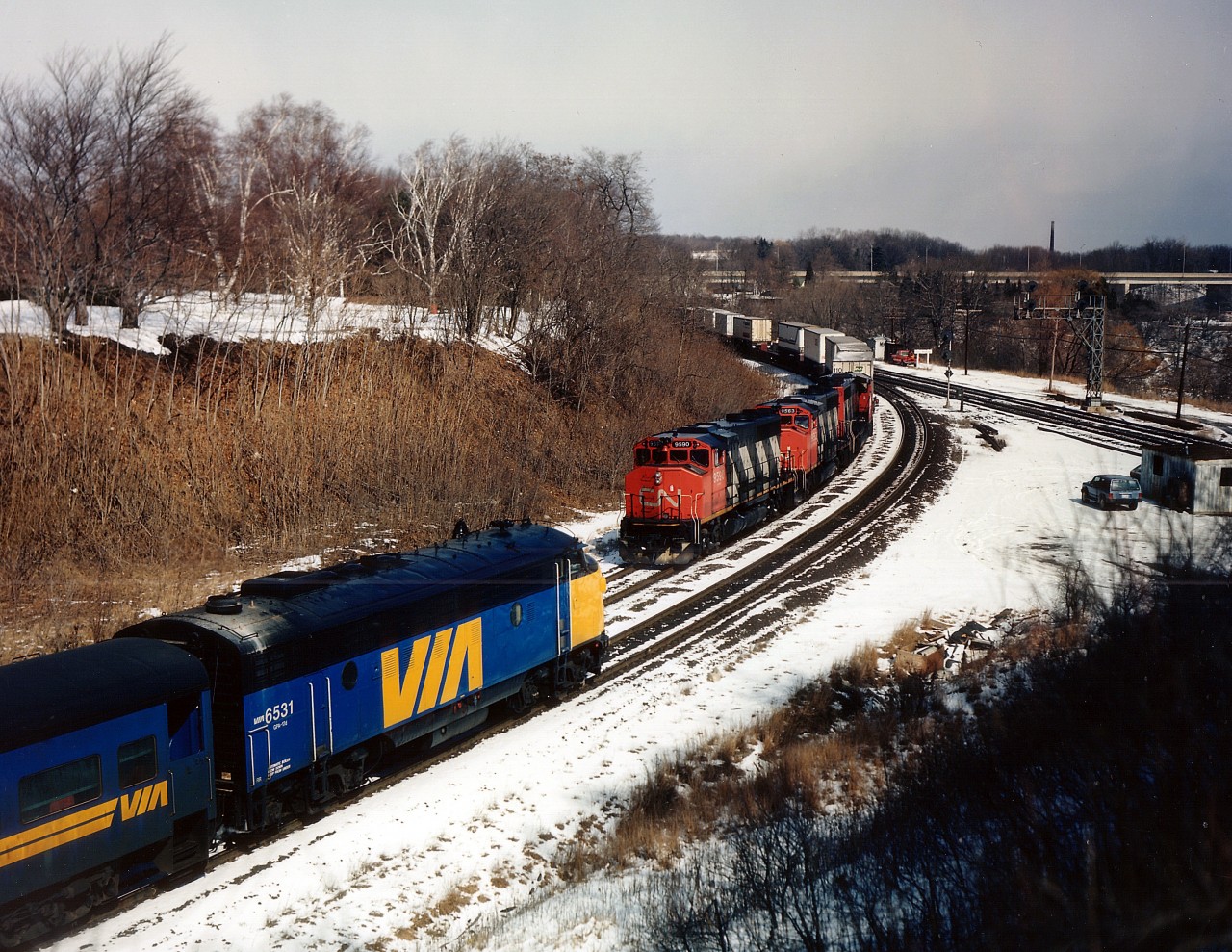 Rather fortunate while waiting for a non-descript westbound CN to have eastbound VIA #72 with a very clean 6531 on the nose pass below me for a good 'meet' image. The westbound is a trio of Widecabs, common at the time, CN 9590, 9563 and 9510, train #425, according to my notes.  March 1st was a Wednesday, so it is quiet at the Junction; and the blue Jeep in the photo belongs to fellow rail enthusiast Pete Hoople.  This photo, as the last RP. upload taken at this location, was shot with colour sheet film, 4x5 inch neg., using an old Speed Graphic. Purchase, processing and an 8x10 image printed would set me back $10+ PER shot, which is why I didn't shoot too many photographs with this format.