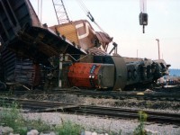 An image such as this brings the real meaning out "She was as ugly as a train wreck" because major wrecks really can be a mess. But, unfortunately, they are a fact of railroading.
On August 5, 1978 CN's #387 was Hamilton-bound from Niagara when it hit an open switch. CN 9404, 4523, 4524 and 4573 piled up along with a considerable number of cars. This image is from August 7th, as late day spectators (a line in the background on the right)watch the cleanup in progress. Track in foreground was once part of the line that ran over the Burlington Beach strip. It was severed when the S.Ck traffic circle on the QEW was removed back in the 1970s.
As much as Lac Megantic has been at the front of the railroad news this year, I feel there were a lot more derailments in the past. In a short stretch I recall major ones at Simcoe, at CN Robbins, at Grimsby, Aldershot and Burlington. No, they did not all get a visit from me.
This derailment was blamed on vandals cutting into the lock at the switch, mile 37.6 Grimsby Sub.
