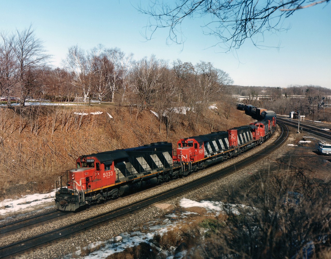 Back in the late 1980s it was always nice to see something other than a trio of Widecabs leading a freight. Here we have CN 5033, 5055,5234, 9455 and 2030 westbound as seen from a favourite location on the hillside at Bayview Jct back when this viewpoint wasn't a cluttered off-limits spot like it is now.
All CN units now off roster but first one: 5033 rebuilt into CN 6010 in 1995, 5055 became UP 4750, no record in CTG so perhaps 5234 scrapped, 9455 sold to Western Rail in 2007 and the big alco went to the scrapper by 1996. The work truck? Oh, he was just some guy stopped for lunch.