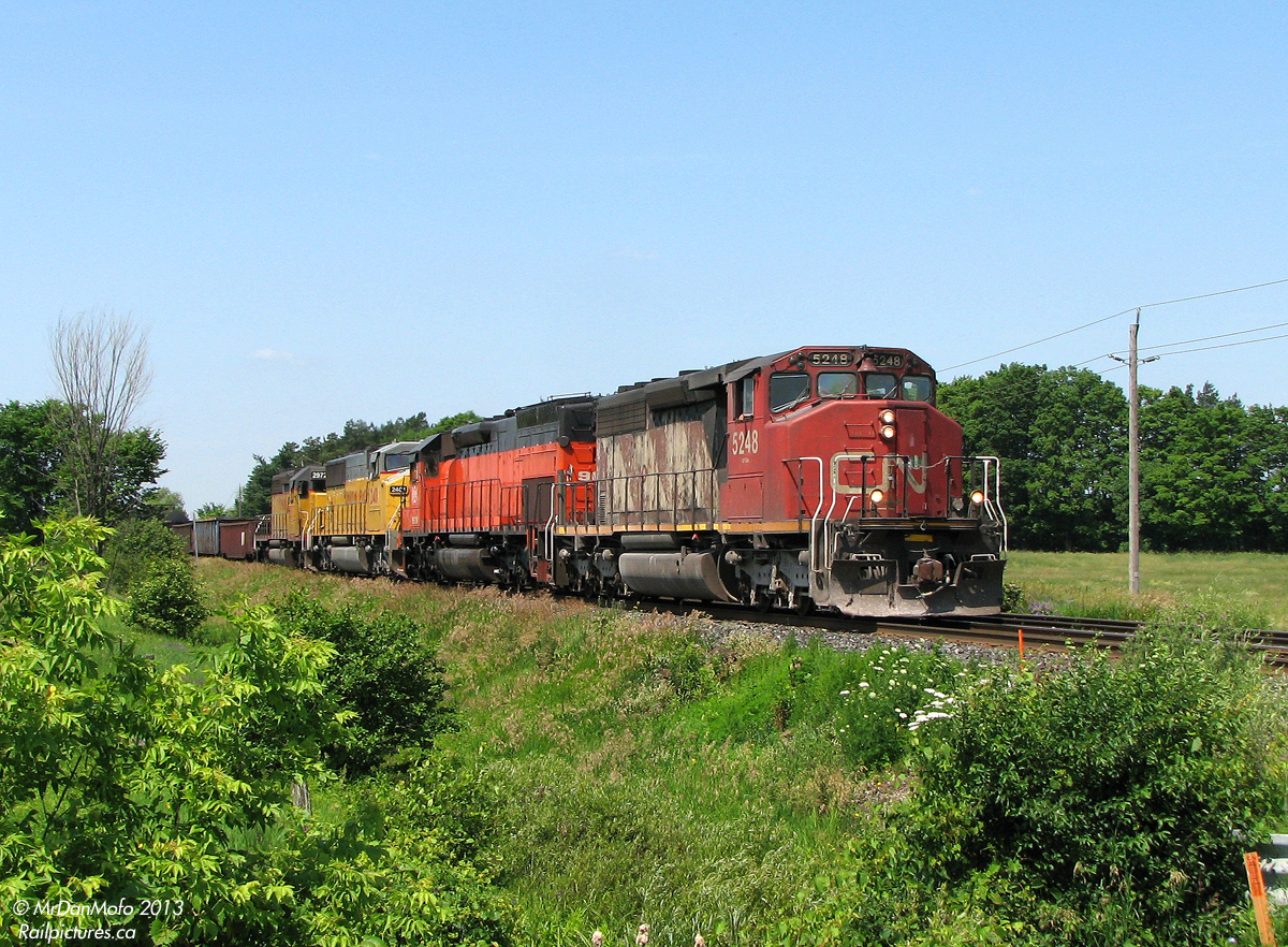 Possibly one of my favourite train consists: beyond the suburban development on a sunny late morning in July of 2008, we find ourselves posed amid the countryside on Mississauga Road for the coming of some Foreign Power goodies.

After VIA #85 rockets by with its usual F40PH + 2 Budds and stops at the Credit for a meet, CN #398 rolls into town with a colourful FPON lashup of epic proportions: a beat-up SD40-2W (CN 5248) leading a rebuilt Bessemer & Lake Erie Tunnel Motor (BLE SD40T-3 909) rarely seen in these parts, and two yellow UP units for good mix (UP SD60M 2401 and SD40-2 2972). The train is still clipping along, but will be slowing shortly for the red track flags and Rule 42 work limits up ahead. Unfortunately, an errant bush obscured a trailing shot of the backwards-facing 909. Eh tu mother nature.

The haul for the afternoon included VIA #85, CN #398, GO #266, CN #393, CN #422, CN #338, and GO #281, but we all know which one took the cake...