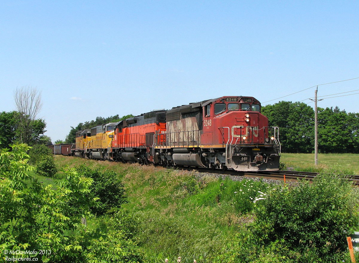 Possibly one of my favourite train consists: beyond the suburban development on a sunny late morning in July of 2008, we find ourselves posed amid the countryside on Mississauga Road for the coming of some Foreign Power goodies.

After VIA #85 rockets by with its usual F40PH + 2 Budds and stops at the Credit for a meet, CN #398 rolls into town with a colourful FPON lashup of epic proportions: a beat-up SD40-2W (CN 5248) leading a rebuilt Bessemer & Lake Erie Tunnel Motor (BLE SD40T-3 909) rarely seen in these parts, and two yellow UP units for good mix (UP SD60M 2401 and SD40-2 2972). The train is still clipping along, but will be slowing shortly for the red track flags and Rule 42 work limits up ahead. Unfortunately, an errant bush obscured a trailing shot of the backwards-facing 909. Eh tu mother nature.

The haul for the afternoon included VIA #85, CN #398, GO #266, CN #393, CN #422, CN #338, and GO #281, but we all know which one took the cake...