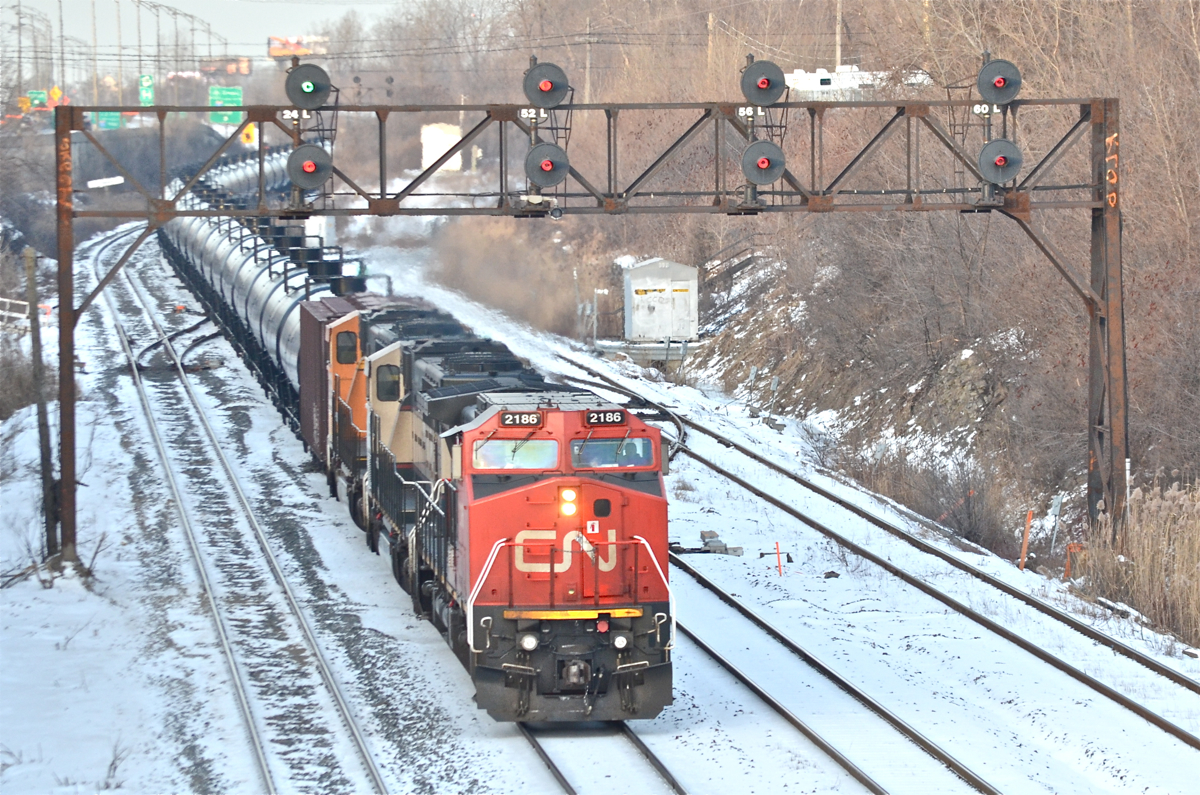 CN 710 heads east led by CN 2186 (ex-BNSF 849), BNSF 9661 & BNSF 9977. Both of these SD70MAC's have been to Quebec during the past couple of weeks on this same oil train. The train is passing the entrance to Taschereau Yard and will stop in a few miles for a crew change at Turcot West. For more train photos, check out http://www.flickr.com/photos/mtlwestrailfan/