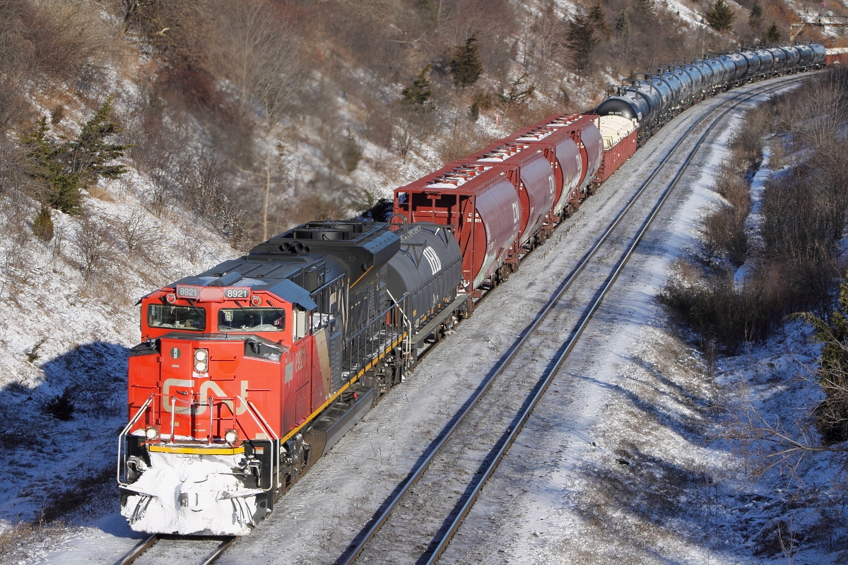 CN 8921 roars around the bend with snow on the plow, bringing a nice mixed freight consist towards Macmillan yard.