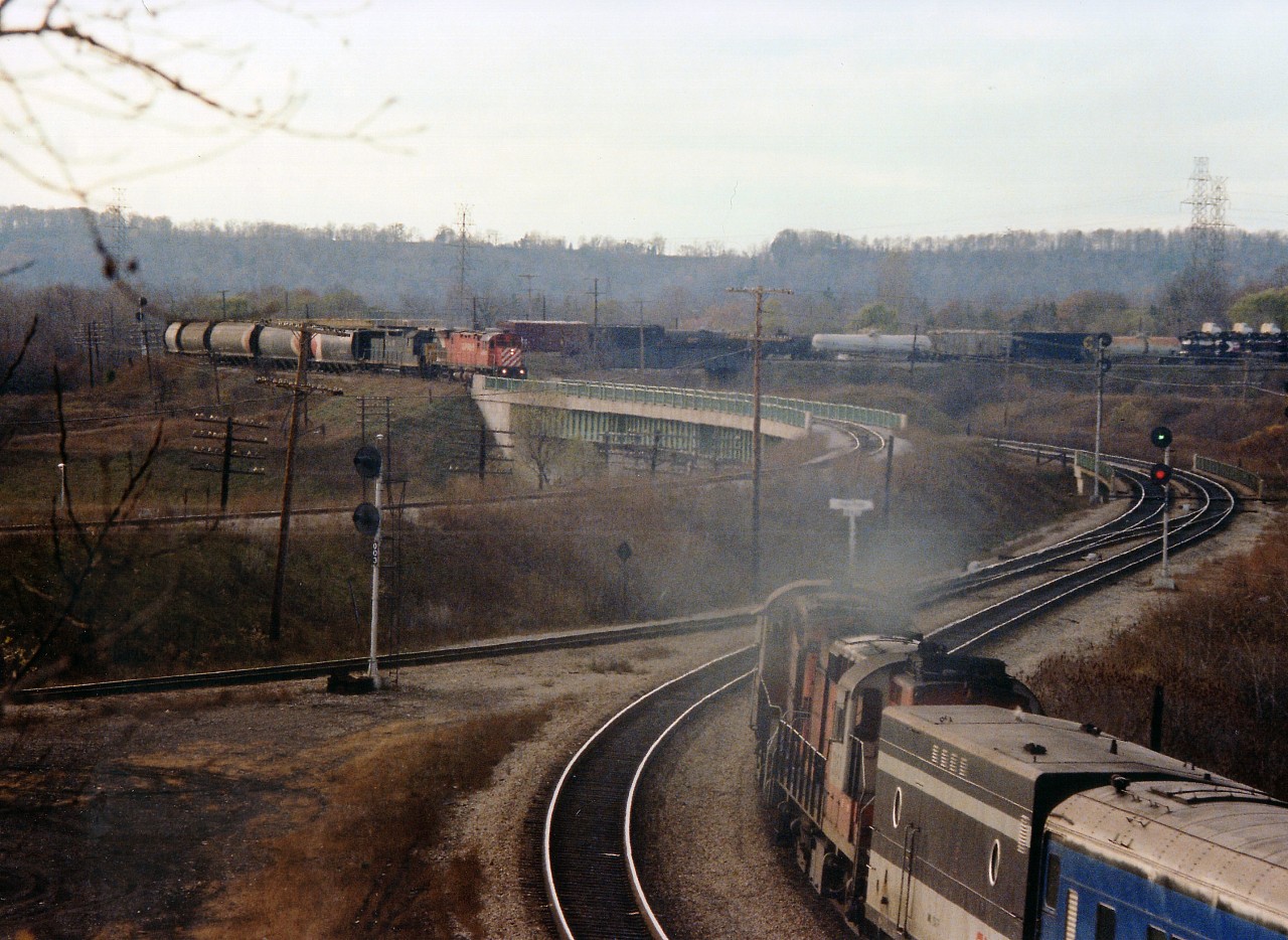 The skies began to clear but the sun was going down when the second train of the infamous Mississauga Wreck detouring down the Goderich line from Guelph Jct finally made the scene. All set to shoot it from the hillside by the track when I heard a rumble behind me. A quick scamper to the CN Dundas sub side netted me this: Late afternoon CN Tempo, 2 units and steam jenny westbound approaching the bridge over the Hwy 403 as the CP 4242 and C&O 3539 did the same southbound.The power would be turned and lead the train out of Hamilton and run to Toronto via the CN Oakville sub., well after dark.  Despite the gloom of the air, this is my favourite image of the "Day After".