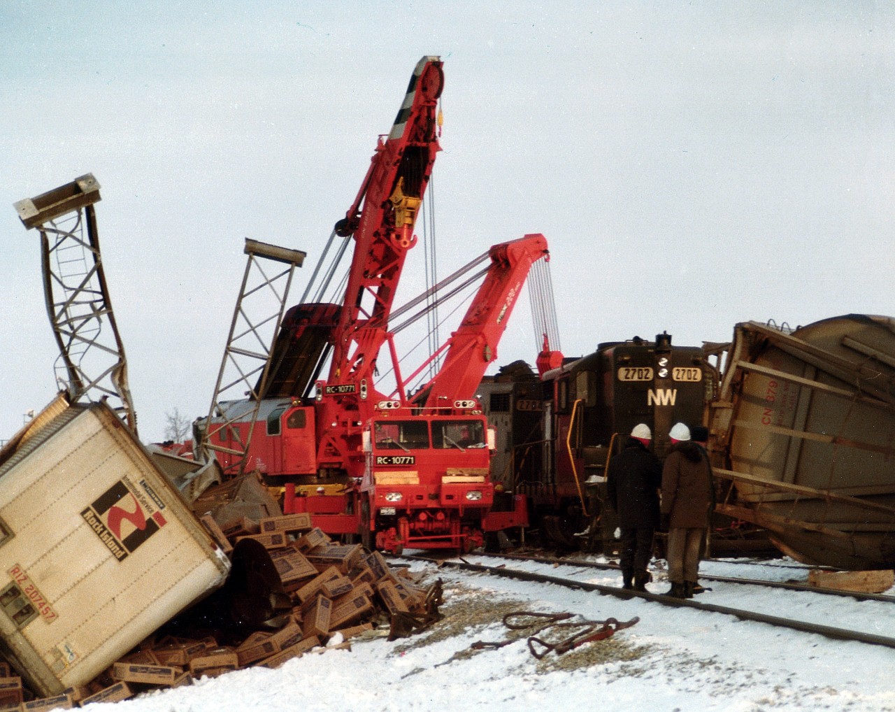 Just before midnight on March 1, 1978, N&W 2704 and 2702 led a train eastbound out of the tunnel under the Welland Canal, running over to CN Robbins where the junction with CN is. For some unknown reason the N&W train missed the stop signal, striking an eastbound CN freight 46 cars back on the 81 car train, derailing 15 CN cars of flour, autos and rubber. A couple of trailers on flats as well of the N&W power left the rails. This photo, taken the next afternoon, shows heavy cranes working to upright the damaged locomotives while the topsy-turvy signal tower bases overlook the scene.