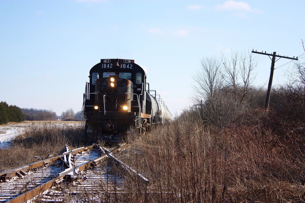 In just over a week the St. Thomas & Eastern will cease operations over the former CN Cayuga sub. RS18 1842 leads a sizeable train past the ghost diamond with the abandoned Canada Southern.