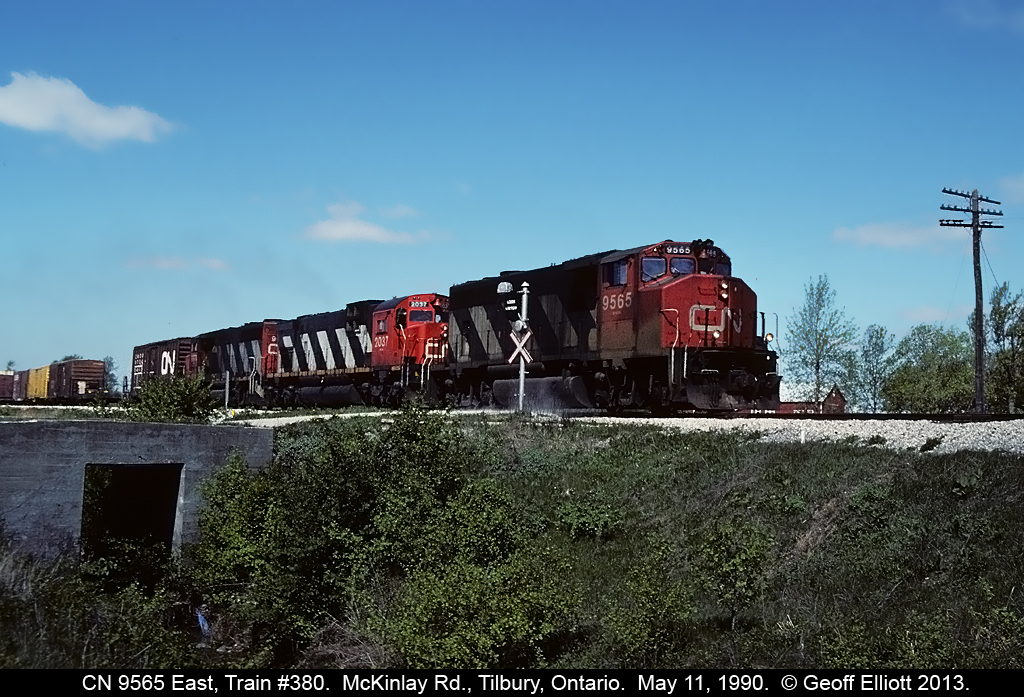 CN 380 kicks up some dust off McKinlay Road crossing just east of Tilbury, Ontario back in 1990.  The wig-wags are working, but I obviously hit the shutter button at the wrong time as the 'banjo' is in the shroud.  Oh well, can't shoot it now as the only thing left in this photo is the cement culvert, the old telegraph pole, and the barn in the background!!!!