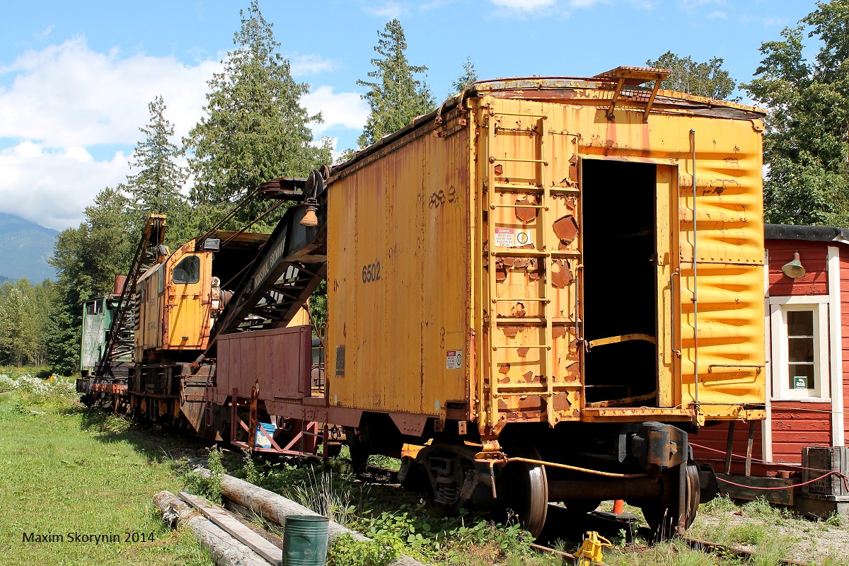 An old retired BC Rail crane rests in a museum in the outskirts of Squamish, BC with a boxcar attaches to it.