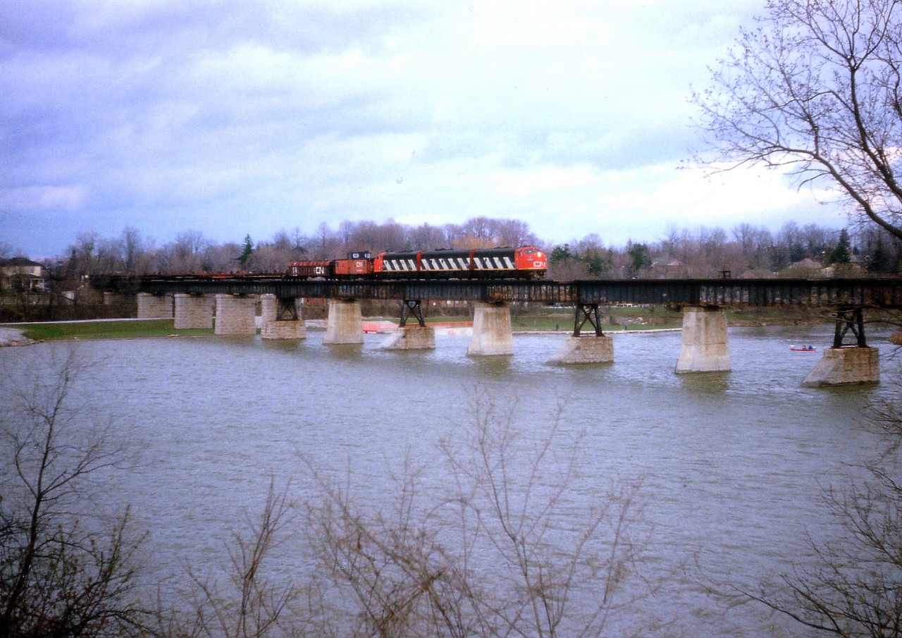 Here's a standard-lens image taken from the south side of the Grand River at Caledonia, showing CN's #725 (steel train) en route to Nanticoke from Hamilton on April 8, 1986. This shot was made to show the size of this bridge and width of the river, as a result the train looks rather diminutive. Power is 9169, 9196 and 9172.