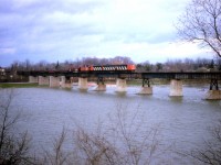 Here's a standard-lens image taken from the south side of the Grand River at Caledonia, showing CN's #725 (steel train) en route to Nanticoke from Hamilton on April 8, 1986. This shot was made to show the size of this bridge and width of the river, as a result the train looks rather diminutive. Power is 9169, 9196 and 9172.