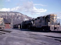 A westbound freight with CN 6189, a 4-8-4 Northern, is assisted by a relatively newer GP9 4506 as they pass by Dundas Station in 1958, with the Niagara Escarpment looming in the background. Another sister GP9 not more than a few years old, 4503, rests on the tracks by the station.