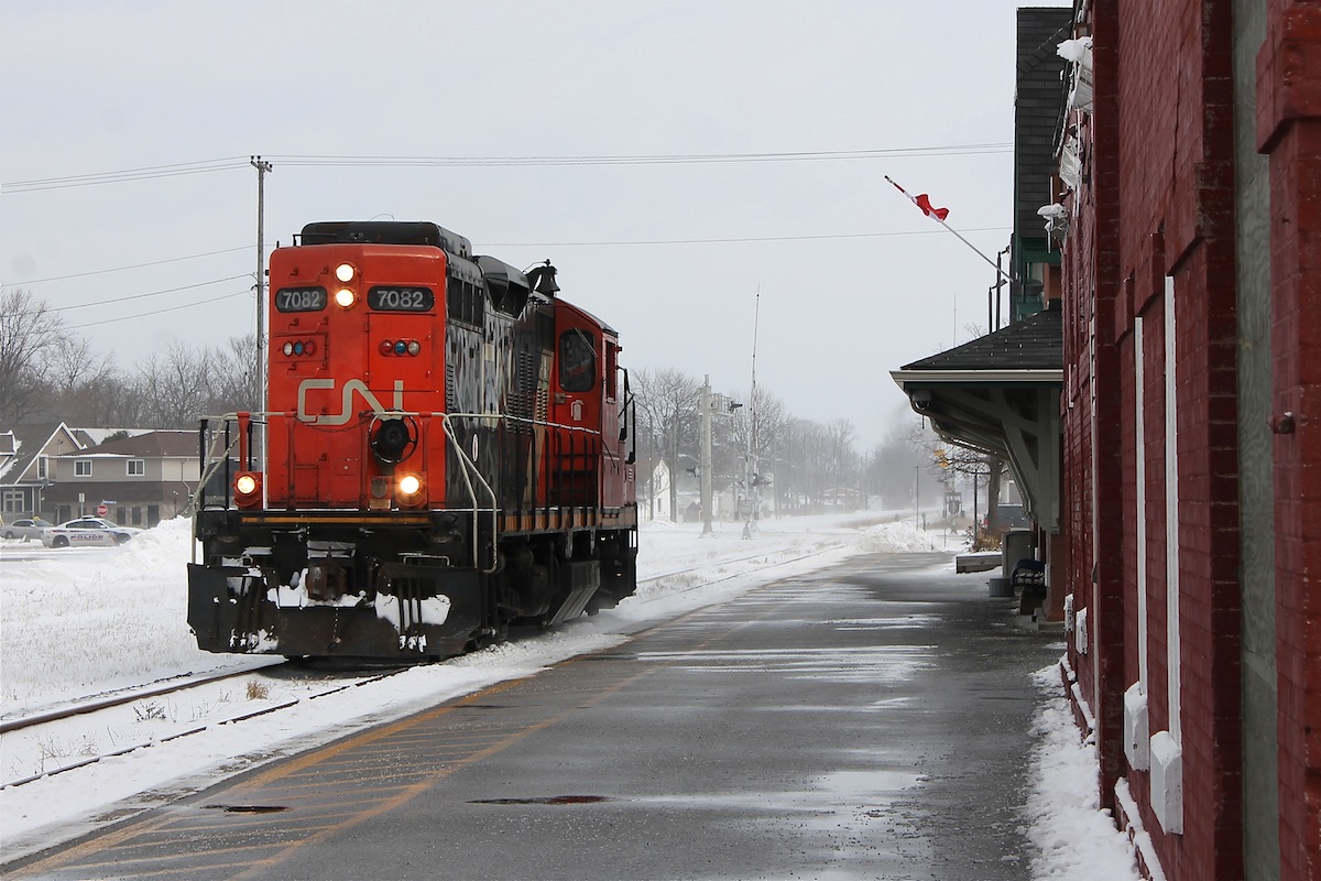 CN GP9RM 7082 trundles long hood forward light power passed the historic GTW passenger depot in Chatham to fetch its cut of grain cars destined for Blenhiem.