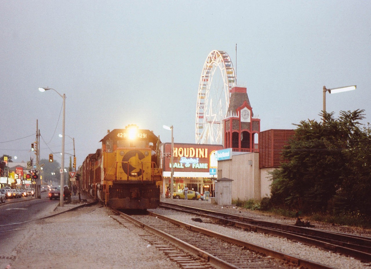 IF you have ever driven on a summer night to downtown Clifton Hill in "The Falls" you know what it is like. Mobs of people and crawling traffic.  I was down that way on a warm summer's eve looking for a chance of catching the evening Chessie (this train came thru earliest at 2050-2100 if I'm lucky) and summer was the only time of the year to get good lighting. Heard nothing on the scanner. I'm coming up to Clifton Hill and, holy (bleep)!!  Its the damn train!!! There is nowhere to park and no time to react, so I put two wheels up on the curb and jumped out. Being almost dark resulted in a very slow shutter speed. Maybe a 30th sec. A lot of wandering tourists and a lot of roadgeeks laid on their horns as they wanted to get to the turning lane I had blocked.......no rush; they had to wait for the train!! This area is a crazy place at best, and when a hundred car train meanders thru at about 10 MPH, it becomes a REALLY crazy place. So, that night, I fit right in. C&O 4291 and 4173 the power. Note it was a double track back in those days. In a few years one track would be taken up, in 20 years it was all gone and tourists could finally wander in peace.