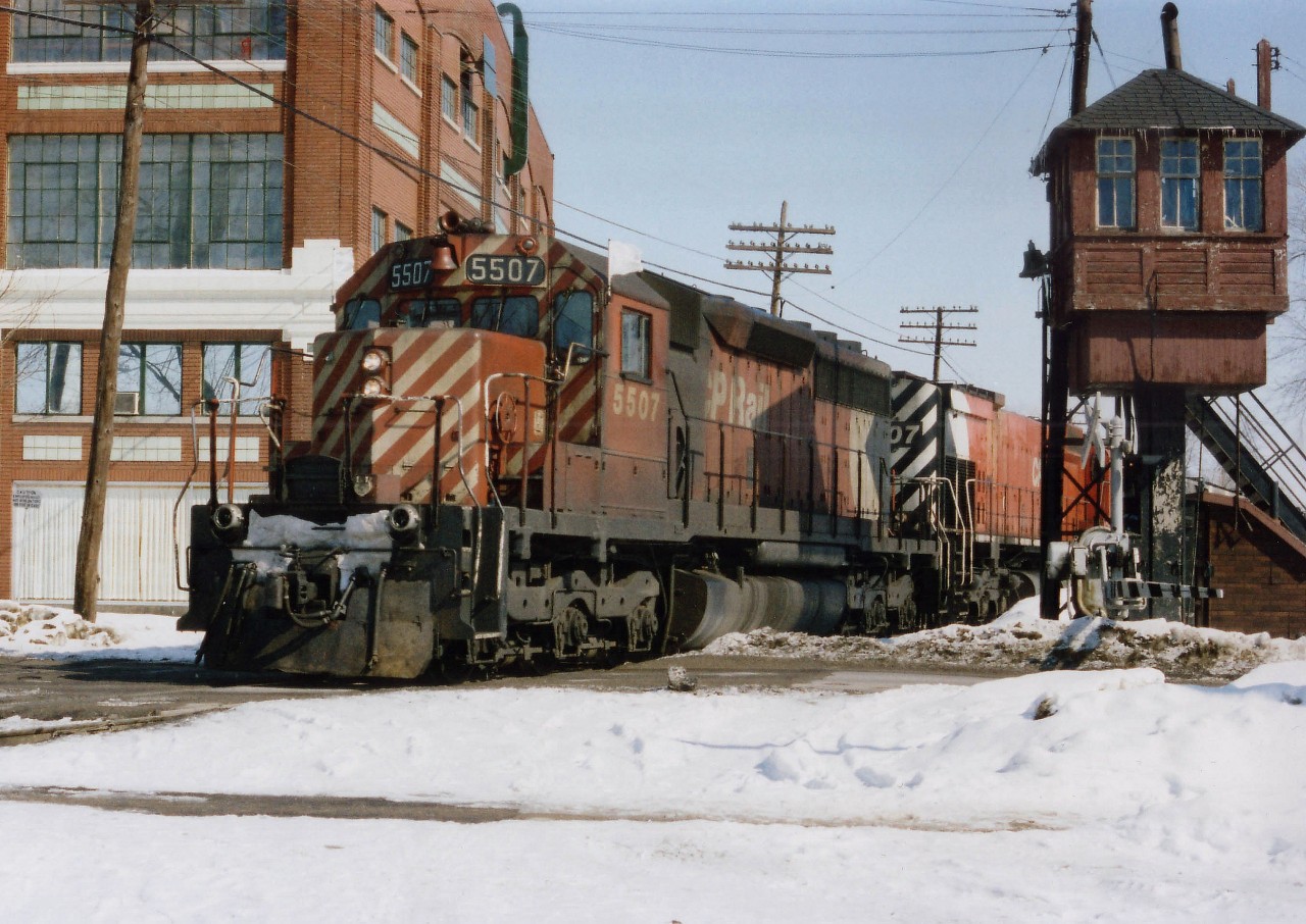 CP 5507, 4707 west; 95 cars and van 434573. The train is passing over Waterloo St. at Pall Mall St., just to the west of the Quebec St. yard. It was amazing to find an old Watchman's Tower still standing in 1978, for these now-rare structures are relics of the steam age. A cabin, built on stilts, gave the watchman a view up and down the line, and he controlled the crossing gates on approach of a train. The bell you can see on the front in the photo clanged to warn pedestrians of the train's presence. A metal chimney for the oil heater sprouts up top. I would imagine not a single example of one of these links to the past is still standing today. Unless, of course, a museum has captured one.