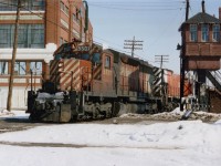 CP 5507, 4707 west; 95 cars and van 434573. The train is passing over Waterloo St. at Pall Mall St., just to the west of the Quebec St. yard. It was amazing to find an old Watchman's Tower still standing in 1978, for these now-rare structures are relics of the steam age. A cabin, built on stilts, gave the watchman a view up and down the line, and he controlled the crossing gates on approach of a train. The bell you can see on the front in the photo clanged to warn pedestrians of the train's presence. A metal chimney for the oil heater sprouts up top. I would imagine not a single example of one of these links to the past is still standing today. Unless, of course, a museum has captured one.
